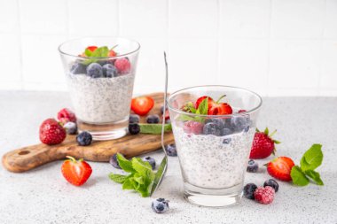 Taze dutlu Chia tohumu pudingi. Sağlıklı yaz kahvaltısı tatlı kremalı süt veya yoğurt, chia, çilek ve yabanmersini, beyaz masa arkaplan fotokopi alanı