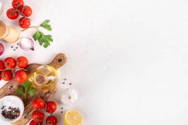 Baharatlar, karabiber, sarımsak, soğan, yeşillik ve domates, beyaz yemek masasında zeytin yağı. Beyaz taş arkaplanda yemek pişirmek için gerekli malzemeler..