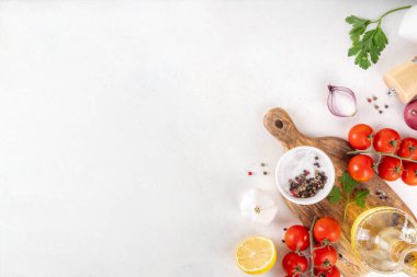 Baharatlar, karabiber, sarımsak, soğan, yeşillik ve domates, beyaz yemek masasında zeytin yağı. Beyaz taş arkaplanda yemek pişirmek için gerekli malzemeler..