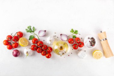 Baharatlar, karabiber, sarımsak, soğan, yeşillik ve domates, beyaz yemek masasında zeytin yağı. Beyaz taş arkaplanda yemek pişirmek için gerekli malzemeler..