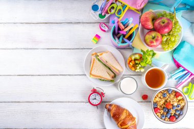 Okul çocukları için sağlıklı besleyici bir sabah kahvaltısı, taze meyve, sebze, kruvasan, müsli, süt ve sandviç. Okuldan ve işten önce kahvaltı yapmak, fotokopi çekmek.