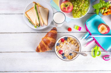 Okul çocukları için sağlıklı besleyici bir sabah kahvaltısı, taze meyve, sebze, kruvasan, müsli, süt ve sandviç. Okuldan ve işten önce kahvaltı yapmak, fotokopi çekmek.