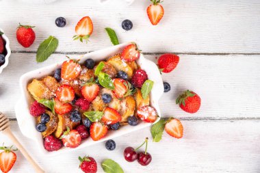 Yaz meyvesi ve Fransız tostu fırınlanmış güveç. Ev yapımı lezzetli Fransız tostu, kremalı kahvaltı pastası, kızarmış ekmek ve taze çilek, yabanmersini, ahududu ve kirazlı.