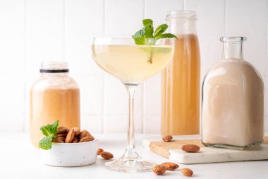 Tatlı ve ekşi limon orgeat kokteyli, Orgeat limonata tarifi, bir martini bardağı alkollü içki ve badem şurubu şişesi.