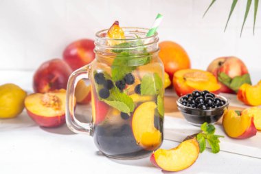 Arnold Palmer Boba topaklı buzlu çay ya da Tapioca incileri, Soğuk Şeftali Limonlu Çay, Mason kavanozunda renkli balonlu limonata, beyaz masa arkasında taze meyveler