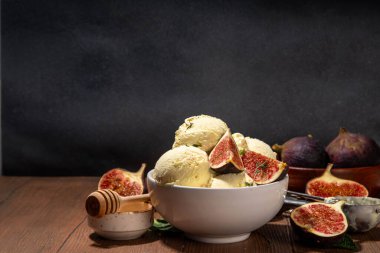 Lezzetli incirli dondurma, aromatik ve kremalı meyveli tatlı, baharatlı tatlı, porsiyonlu kâse, ahşap kaplama, bütün ve ince incir dilimleri, kopyalama alanı.