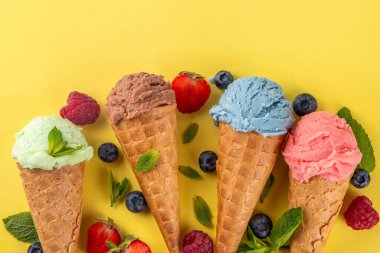  Parlak arka planda waffle külahlı renkli parlak dondurma. Taze böğürtlenli farklı dondurma külahları üst görünüm fotokopi alanı arka planı