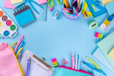 Okul ekipmanları parlak mavi düz yerde yatıyordu. Çeşitli okul ve ofis malzemeleri, aksesuarlar. Okul satışına geri dön. Üst görünüm kopyalama alanı