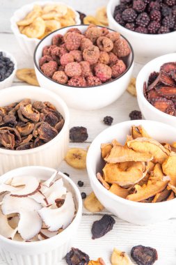 Dondurulmuş meyveler, yaz hasadını depolamak için alternatif bir yol. Kurumuş kurutulmuş ahududu, yabanmersini, şeftali, muz, kayısı, erik, böğürtlen, elma, beyaz ahşap arka planda kiraz.
