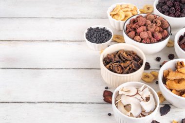 Dondurulmuş meyveler, yaz hasadını depolamak için alternatif bir yol. Kurumuş kurutulmuş ahududu, yabanmersini, şeftali, muz, kayısı, erik, böğürtlen, elma, beyaz ahşap arka planda kiraz.