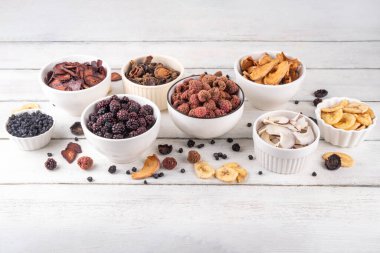 Dondurulmuş meyveler, yaz hasadını depolamak için alternatif bir yol. Kurumuş kurutulmuş ahududu, yabanmersini, şeftali, muz, kayısı, erik, böğürtlen, elma, beyaz ahşap arka planda kiraz.