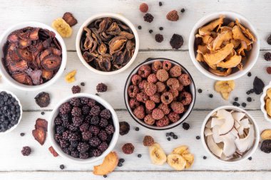 Dondurulmuş meyveler, yaz hasadını depolamak için alternatif bir yol. Kurumuş kurutulmuş ahududu, yabanmersini, şeftali, muz, kayısı, erik, böğürtlen, elma, beyaz ahşap arka planda kiraz.