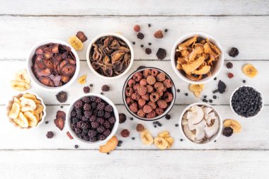 Dondurulmuş meyveler, yaz hasadını depolamak için alternatif bir yol. Kurumuş kurutulmuş ahududu, yabanmersini, şeftali, muz, kayısı, erik, böğürtlen, elma, beyaz ahşap arka planda kiraz.