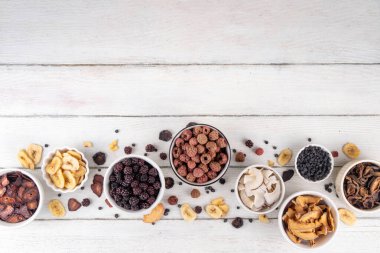Dondurulmuş meyveler, yaz hasadını depolamak için alternatif bir yol. Kurumuş kurutulmuş ahududu, yabanmersini, şeftali, muz, kayısı, erik, böğürtlen, elma, beyaz ahşap arka planda kiraz.