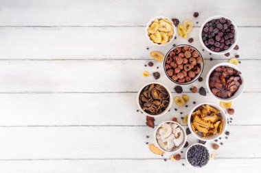 Dondurulmuş meyveler, yaz hasadını depolamak için alternatif bir yol. Kurumuş kurutulmuş ahududu, yabanmersini, şeftali, muz, kayısı, erik, böğürtlen, elma, beyaz ahşap arka planda kiraz.