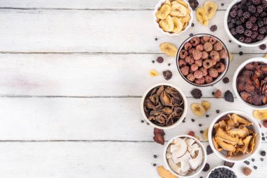 Dondurulmuş meyveler, yaz hasadını depolamak için alternatif bir yol. Kurumuş kurutulmuş ahududu, yabanmersini, şeftali, muz, kayısı, erik, böğürtlen, elma, beyaz ahşap arka planda kiraz.