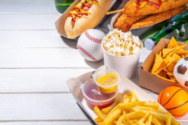 Geleneksel spor stadyumu yemekleri ve bira arka planı, çeşitli beyzbol, basketbol, futbol fanatikleri ve stadyum atıştırmalıkları, cips, sos, bira şişeli sosisliler ve fan aksesuarları. 