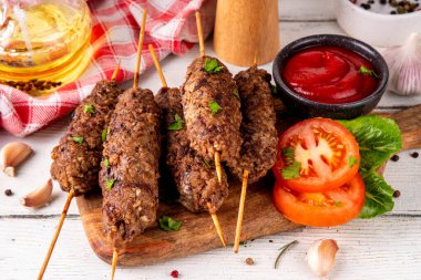 Çubuklu şiş kebap, kıymalı kıymadan yapılır. Lula kebap, geleneksel Kafkas yemeği, ketçap, baharat ve sebze salatası, barbekü ızgara pişirme arka planı fotokopi alanı yukarıda. 