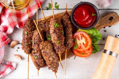 Çubuklu şiş kebap, kıymalı kıymadan yapılır. Lula kebap, geleneksel Kafkas yemeği, ketçap, baharat ve sebze salatası, barbekü ızgara pişirme arka planı fotokopi alanı yukarıda. 