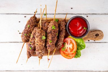 Çubuklu şiş kebap, kıymalı kıymadan yapılır. Lula kebap, geleneksel Kafkas yemeği, ketçap, baharat ve sebze salatası, barbekü ızgara pişirme arka planı fotokopi alanı yukarıda. 
