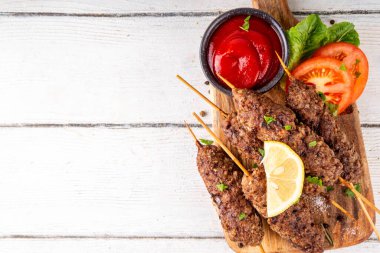 Çubuklu şiş kebap, kıymalı kıymadan yapılır. Lula kebap, geleneksel Kafkas yemeği, ketçap, baharat ve sebze salatası, barbekü ızgara pişirme arka planı fotokopi alanı yukarıda. 