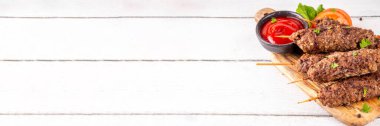 Çubuklu şiş kebap, kıymalı kıymadan yapılır. Lula kebap, geleneksel Kafkas yemeği, ketçap, baharat ve sebze salatası, barbekü ızgara pişirme arka planı fotokopi alanı yukarıda. 