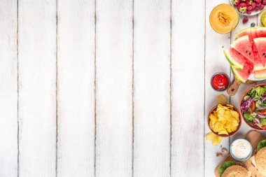 Yaz pikniği ya da barbekü ya da öğle yemeği geçmişi, hamburgerli lezzetli barbekü masası, salatalar, meyveler, karpuz, soslar ve aperatifler. Yaz ailesi ve arkadaşları piknik yiyecekleri topluyor, yer kopyalıyor.