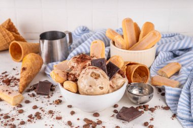 Lezzetli tiramisu dondurması, kahve şurubu, savoyardi kurabiyeleri, çikolata, kakao tozu. Bir kase İtalyan tiramisu tatlı dondurması, dondurmalı waffle konileri, kahve çekirdekleri, malzemeler.