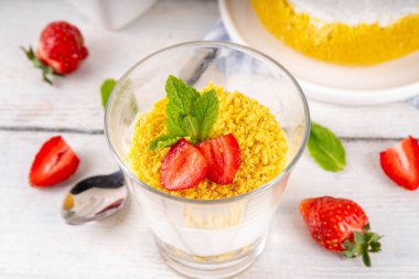 Klasik cam kaplı cheesecake, taze çilekli ve altın kurabiyeli. Katmanlı cheesecake tatlısıyla beyaz ahşap masa üzerinde taze çilekler fotokopi alanı