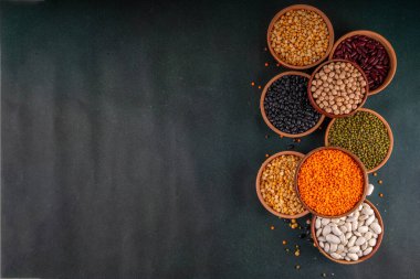 Çeşitli kuru fasulyeler, mercimek, mung, nohut, ahşap kaselerde bezelye çeşitleri. Legumes beyaz masa üst görünümünde. Vegan protein kaynakları yiyecek, kopyalama alanı