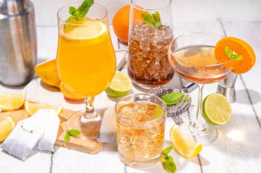 Modaya uygun çay seti yeşil, oolong, siyah, çay ve diğer çay karışımlarından esinlenilmiştir. Soda, şerbetli soğuk yaz içecekleri, limon, kireç ve nane, güneşli beyaz ahşap arka plan.