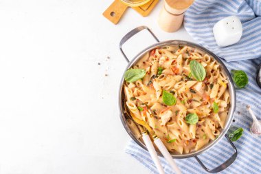 Son moda viral benimle tavuk makarnası evlen. Bir tencere yumuşak makarna ve kremalı ve peynirli sulu tavuk parçaları, sarımsaklı güneşte kurutulmuş domates sosu, nükteli fesleğen yaprağı, tabak ve demlikte.