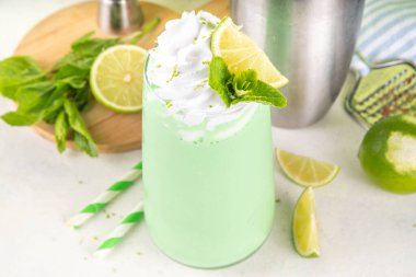 Limonlu turta ya da mojito soğuk milkshake kokteyli. Krem şantili, naneli ve limonlu tatlı ekşi kremalı içecek, beyaz ve yeşil limonlu parlak arka plan. 