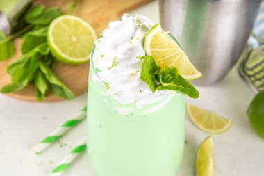 Limonlu turta ya da mojito soğuk milkshake kokteyli. Krem şantili, naneli ve limonlu tatlı ekşi kremalı içecek, beyaz ve yeşil limonlu parlak arka plan. 