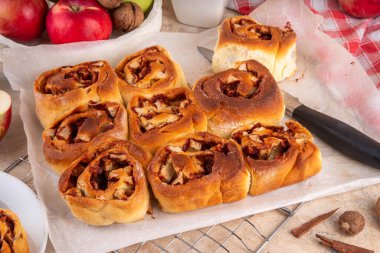 Elmalı tarçınlı çörek, elmalı tarçınlı çörek. Viral elmalı çörekler, bej masada tarçın çubukları, elmalar, fındıklar ve baharatlarla.