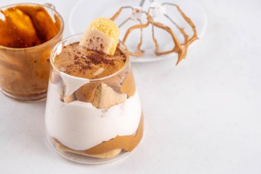 Moda dalgona tiramisu tatlısı. İki bardak kremalı kremalı kahve tiramisu, üzerine de hazır kahve köpüğü ve savoyardi.