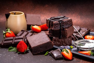 Böğürtlenli siyah çikolatalı kek. Üzerine çikolata sosu serpiştirilmiş ev yapımı kek kurabiyeleri ve koyu arkaplanda taze çilek, yabanmersini, fotokopi alanı.