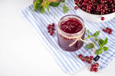 Mutfak masasında taze böğürtlen bulunan küçük kavanozdaki organik kırmızı frenk üzümü reçeli ya da marmelat.