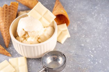 Beyaz çikolatalı dondurma. Porsiyonlu kase beyaz çikolatalı dondurma, soğuk kremalı tatlı, dondurma külahlı ve çikolata dilimli masa, fotokopi masası.