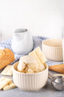 Beyaz çikolatalı dondurma. Porsiyonlu kase beyaz çikolatalı dondurma, soğuk kremalı tatlı, dondurma külahlı ve çikolata dilimli masa, fotokopi masası.