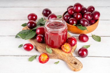 Küçük kavanozda kiraz eriği reçeli. Ev yapımı sonbahar kırmızı kirazlı erik reçeli ve taze meyveli reçel. Sonbahar hazırlıkları, meyve reçelleri tahta masa arkaplan kopyalama alanı üzerinde konserveler