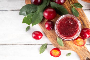 Küçük kavanozda kiraz eriği reçeli. Ev yapımı sonbahar kırmızı kirazlı erik reçeli ve taze meyveli reçel. Sonbahar hazırlıkları, meyve reçelleri tahta masa arkaplan kopyalama alanı üzerinde konserveler