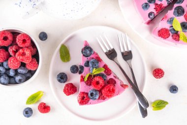 Yaz meyveli ve fırınlanmamış peynirli kek. Kremalı pasta ve çikolatalı kek, pembe peynir tabakası, yabanmersini, ahududu, çilek, nane yaprağı, beyaz masa fotokopisi alanı.