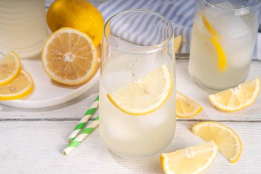 Buzlu ev yapımı limonata, naneli limonlu limonata kokteyli ve beyaz ahşap mutfak arka planında limonlar.