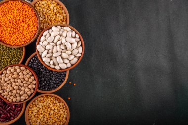 Çeşitli kuru fasulyeler, mercimek, mung, nohut, ahşap kaselerde bezelye çeşitleri. Legumes beyaz masa üst görünümünde. Vegan protein kaynakları yiyecek, kopyalama alanı
