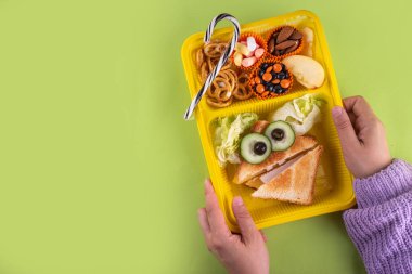 Cadılar Bayramı komik çocuklar, krakerli okul yemeği, sağlıklı peynirli sandviç, kurabiye ve ikramlar, parlak renkli arka plan fotokopi alanı üst görünümü.