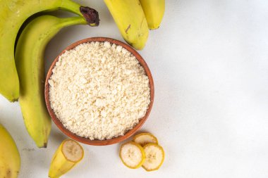 Alternatif organik muz unu taze taze ve dilimlenmiş yeşil muzlar beyaz masa arkasında.