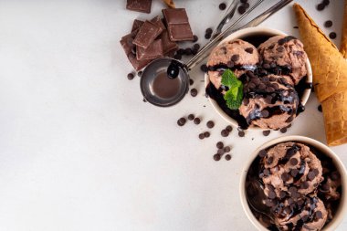 Beyaz masa arkasında dondurma külahlı duble çikolatalı dondurma kasesi. Ev yapımı çikolatalı dondurma ve çikolata sosu, tatlı ve lezzetli yaz tatlısı.