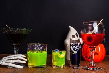 Cadılar Bayramı partisinin şenlik içeceği, çeşitli renkli içkiler, alkolsüz kokteyller, Cadılar Bayramı karakterleriyle içkiler, kostümler, tatil dekorları ve semboller.