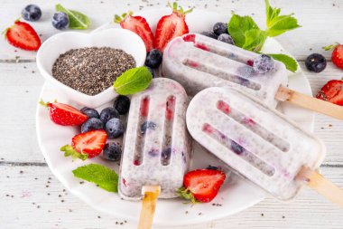 Chia tohumu dondurması lolipop, ev yapımı sağlıklı detoks dondurma kremalı yoğurt, kea tohumu ve taze yaz meyvesi, beyaz masa fotokopi alanı üzerinde.